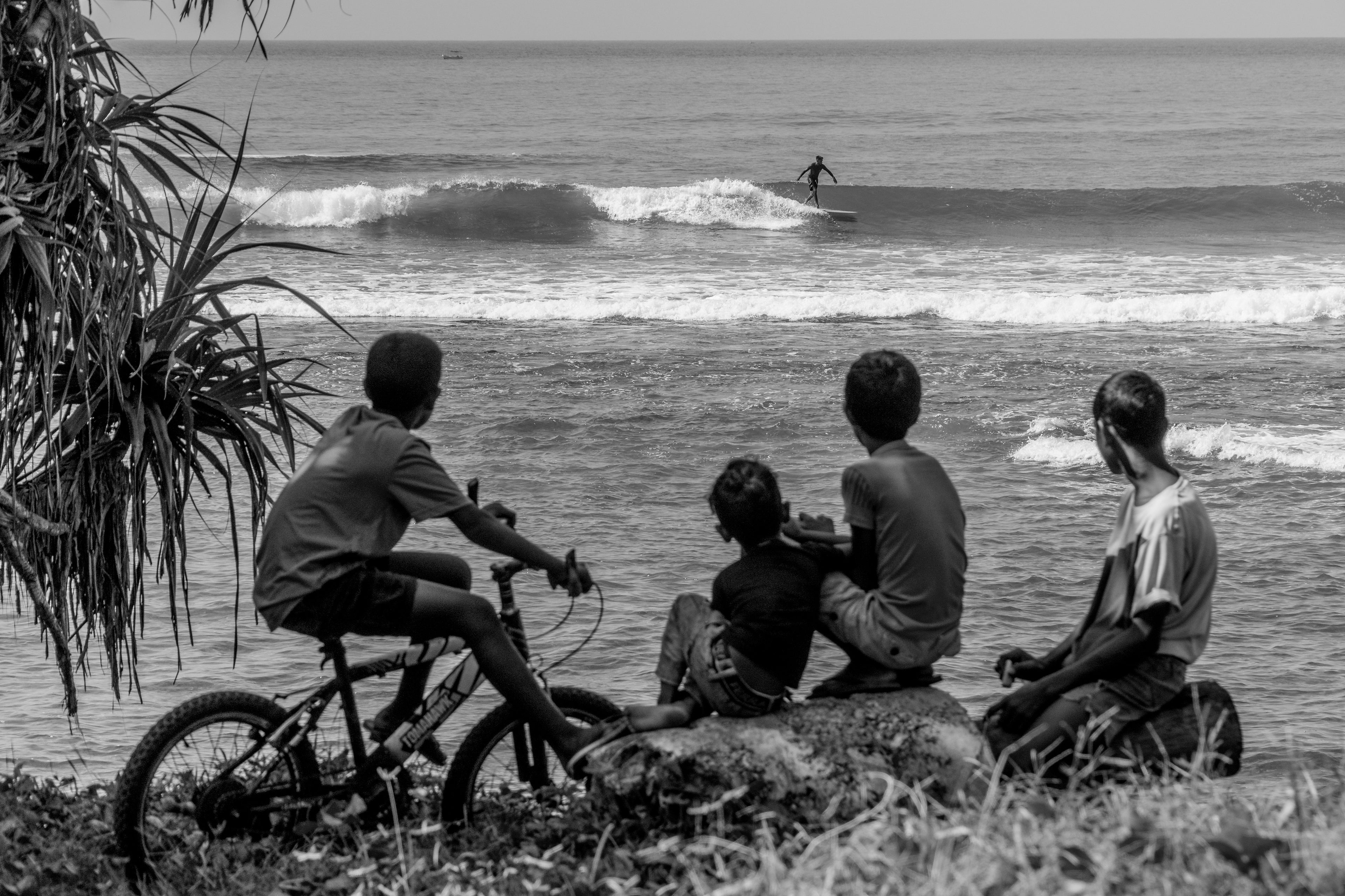 Photo of longboard surfer and local children in Sri Lanka