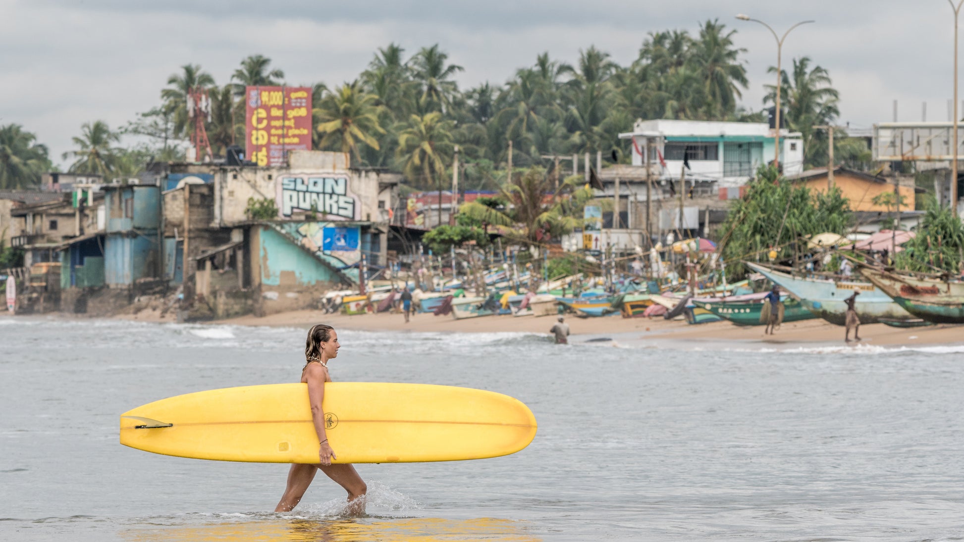 Photo of a longboard surfing lesson in Weligama Sri Lanka, girl carrying a longboard